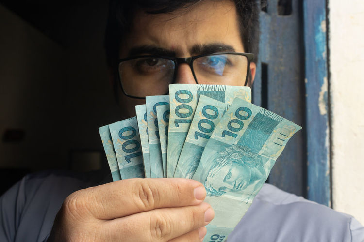 Portrait of man holding banknotes at home