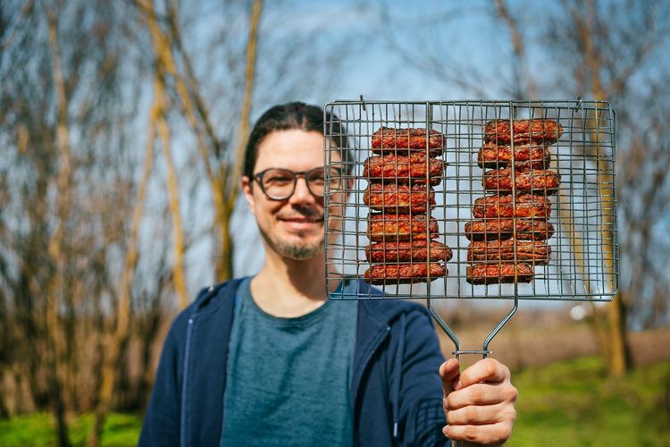 Person holding barbecue meat on grill