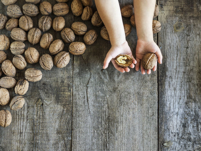 Directly above view of kid holding walnuts on table