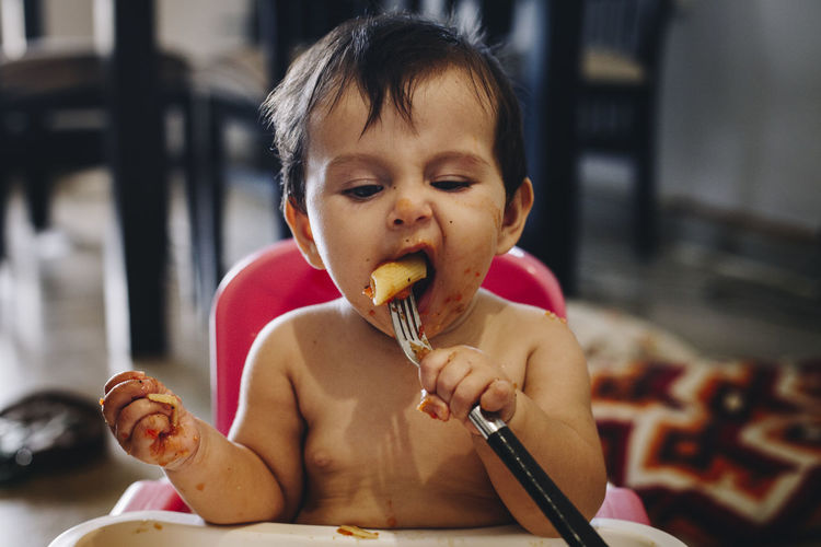 Cute boy eating pasta at home