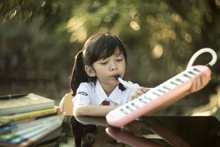 Cute girl playing piano while sitting at desk