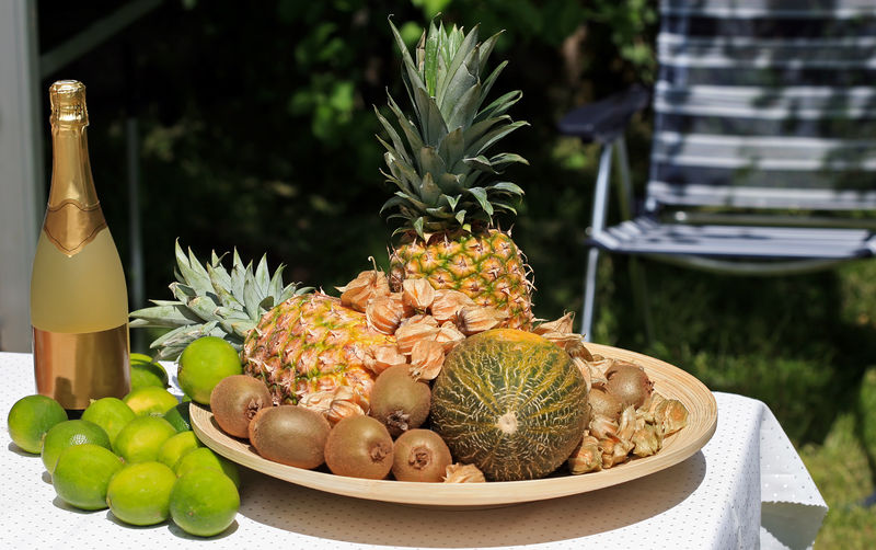 High angle view of various fruits and champagne bottle on table in yard