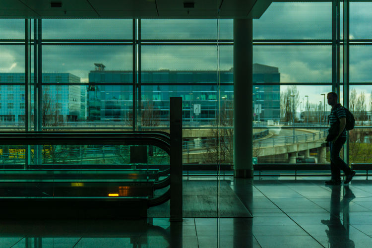 Side view of man walking by escalator at airport