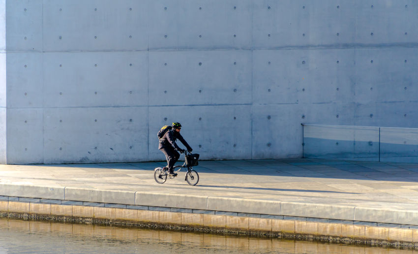 Mature man riding bicycle on street by river