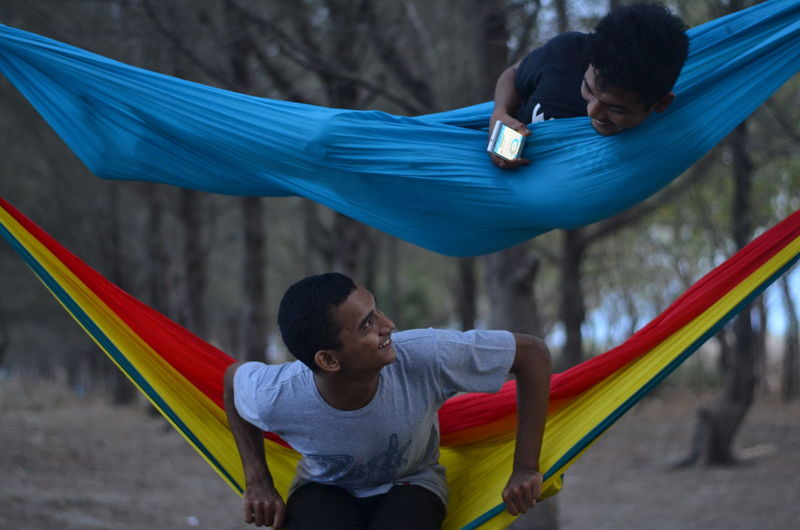 Playful men on hammocks in forest