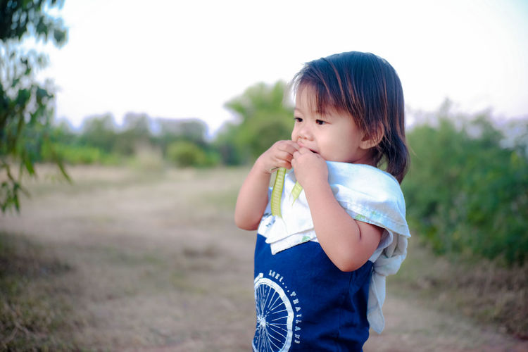Girl eating green pea while standing on land
