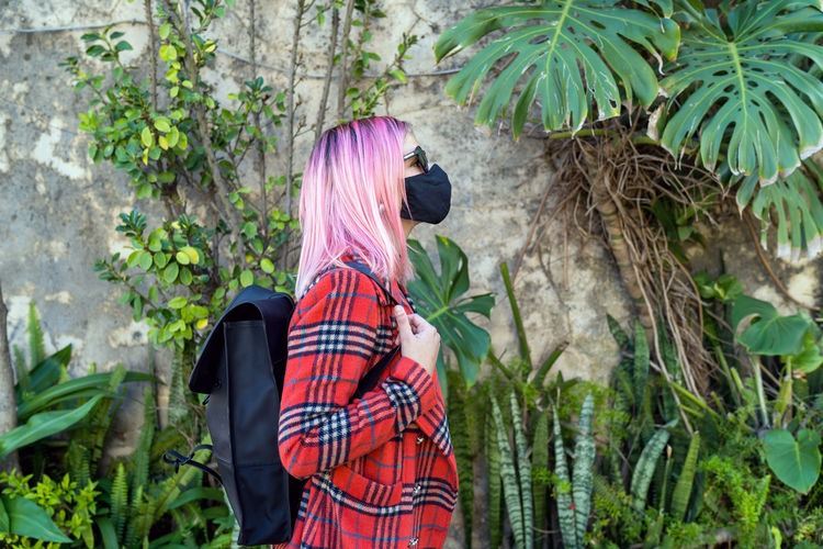 Traveler woman with mask in protection to the pandemic observes
the exotic travel vegetation
