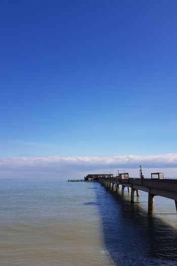 Pier over sea against blue sky