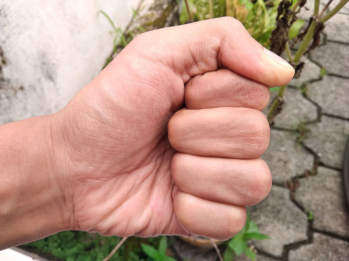 A young man's left hand with a strong fist, exotic skin tone, southeast asian man, close-up hand
