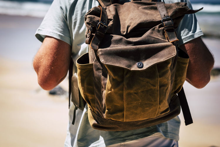 Midsection of man wearing backpack at beach