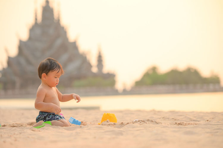 Full length of shirtless baby boy on beach