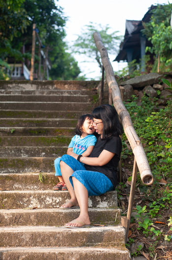Young woman and preschool girl sitting on steps