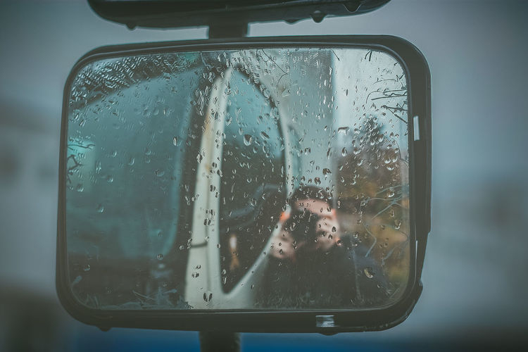 Reflection of man on wet window in rainy season
