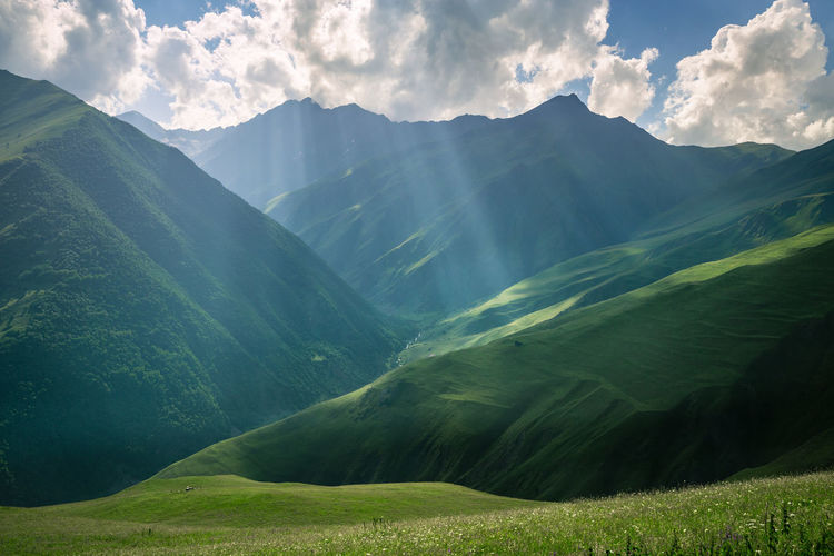 Beautiful rays of the sun in the mountains illuminate the green slopes.