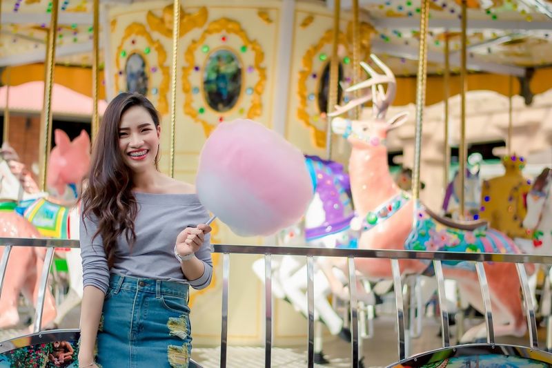 Portrait of cheerful woman standing at amusement park
