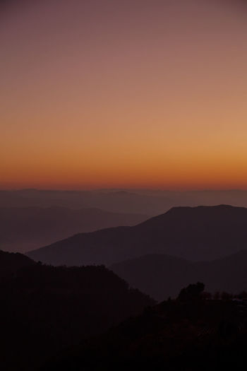 Scenic view of silhouette mountains against orange sky