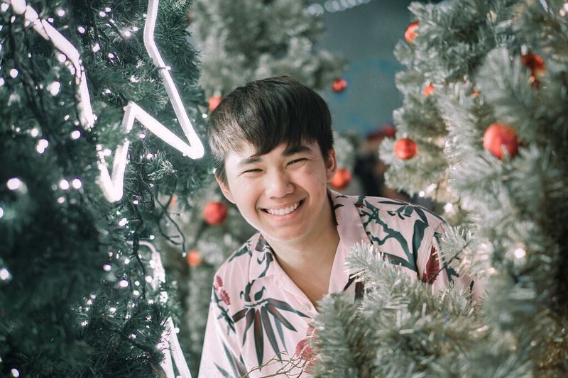 Portrait of smiling man amidst christmas tree