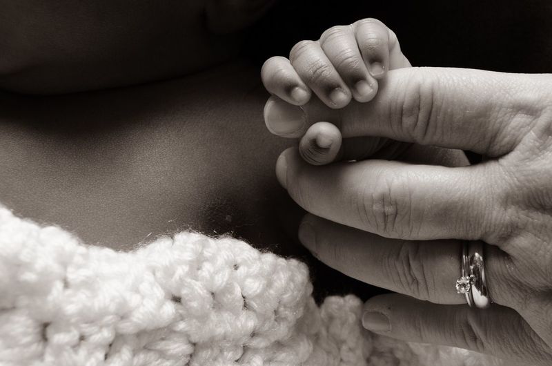 Cropped hand of baby holding mother