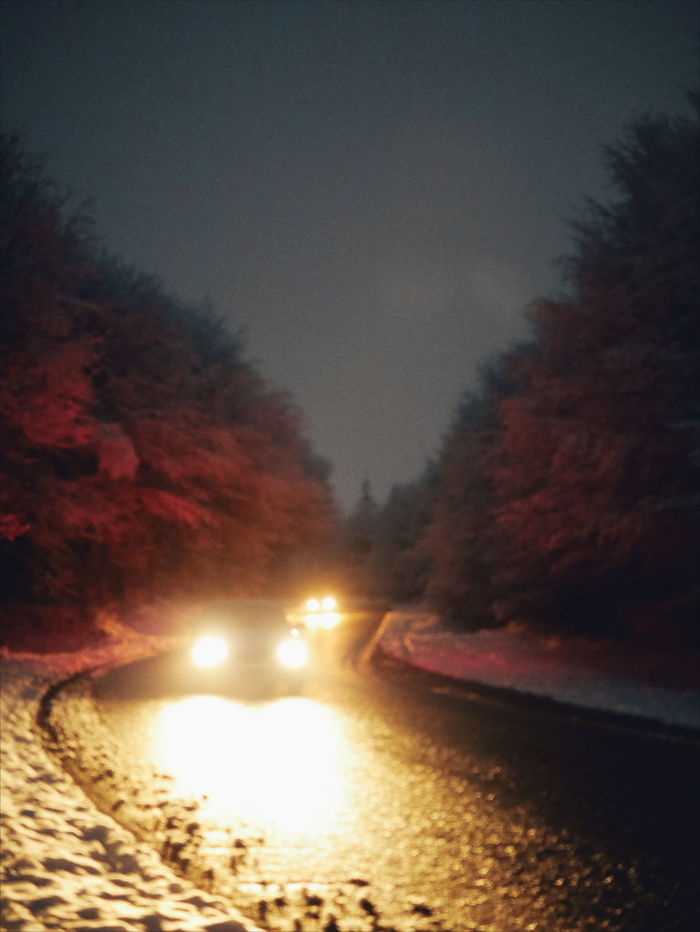 CLOSE-UP OF ILLUMINATED ROAD AGAINST SKY AT NIGHT