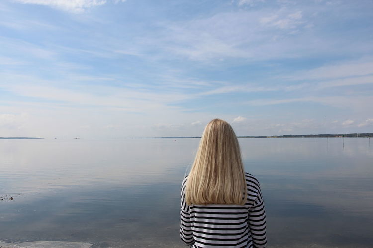 Rear view of girl looking at sea against sky