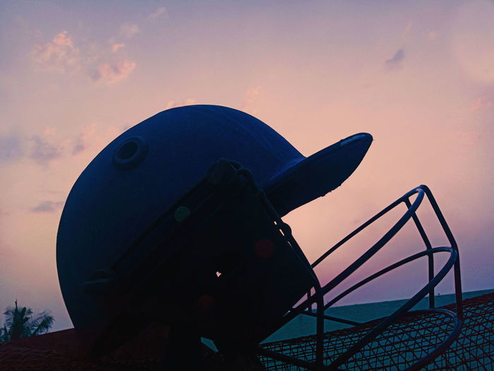 Close-up of helmet railing against sky during sunset