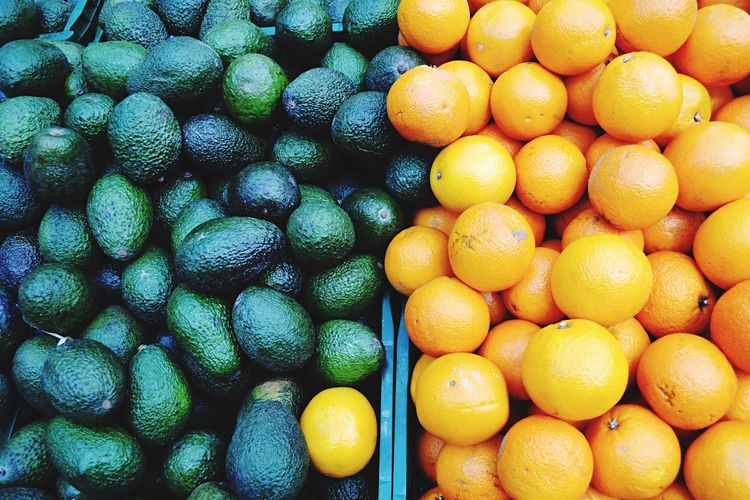 Full frame shot of oranges with avocadoes for sale at market stall