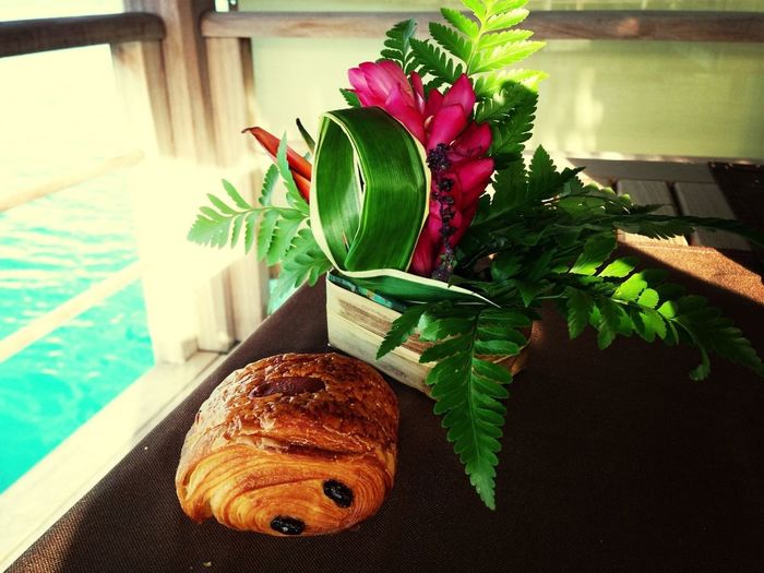 Close-up of croissant and flower pot on table in boat