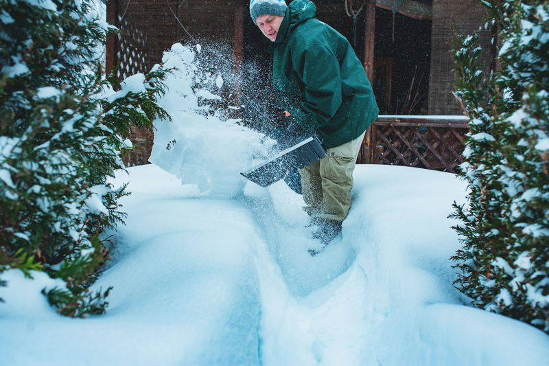 Man removing snow with shovel outside house