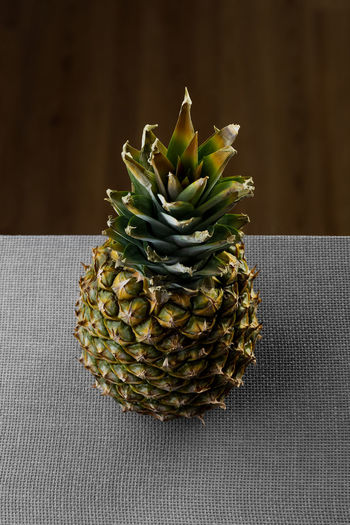 A whole pineapple is viewed from above and isolated on a split textured surface. 