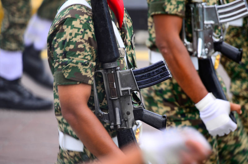 Midsection of soldiers holding weapons