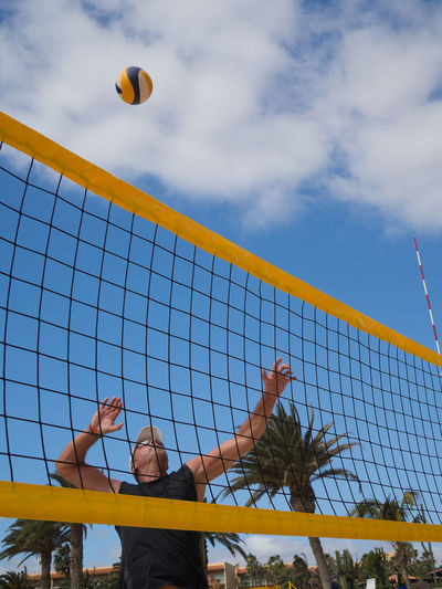 Man playing volleyball at beach against sky