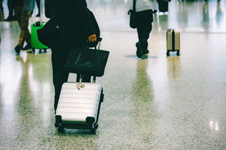 Low section of people walking with luggage at airport