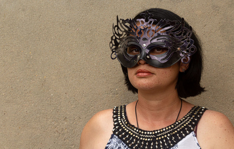 Portrait of woman wearing mask against wall