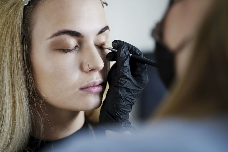 Make-up artist applying eyeshadow on customer's eyelid in salon