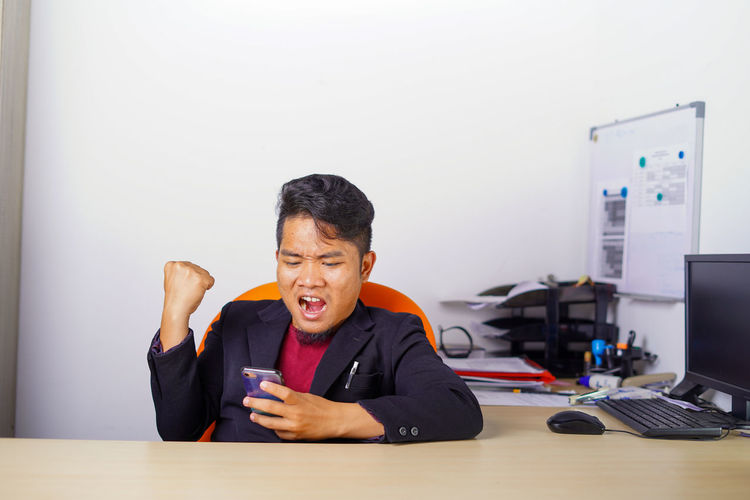 Man using mobile phone while sitting on table