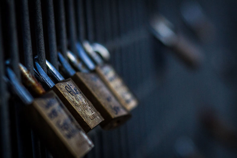 Close-up of rusty padlocks hanging on railing