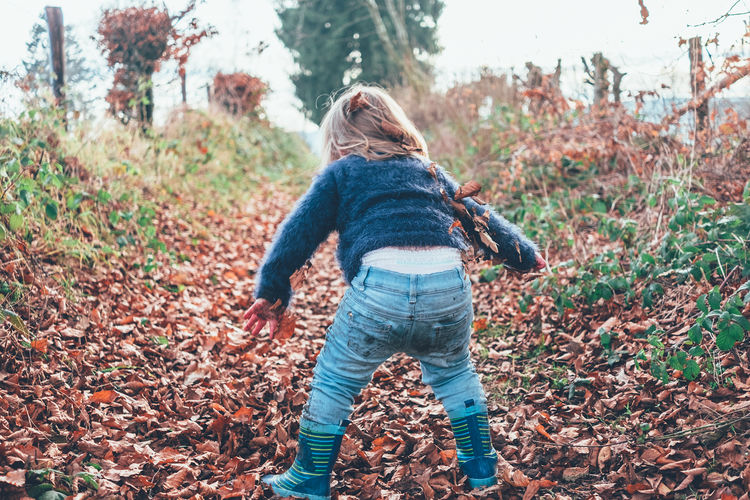 Rear view of girl standing on field during autumn