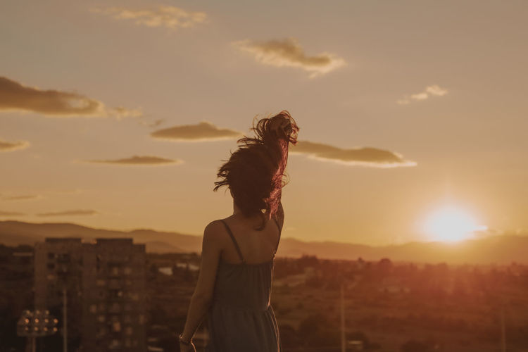 Mature woman standing on terrace against during sunset