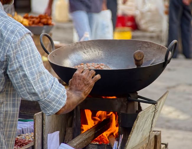 Cropped image of vendor roasting peanuts at market