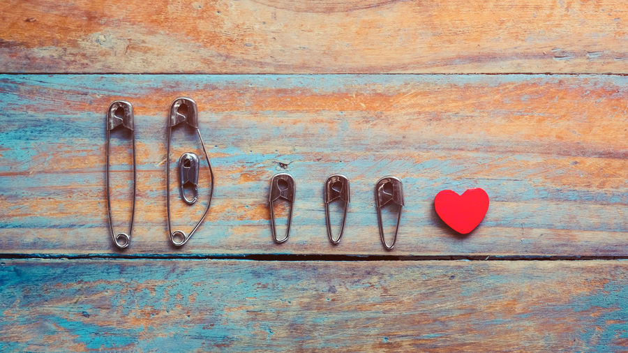 Close-up of safety pins with heart shape decoration on wooden table