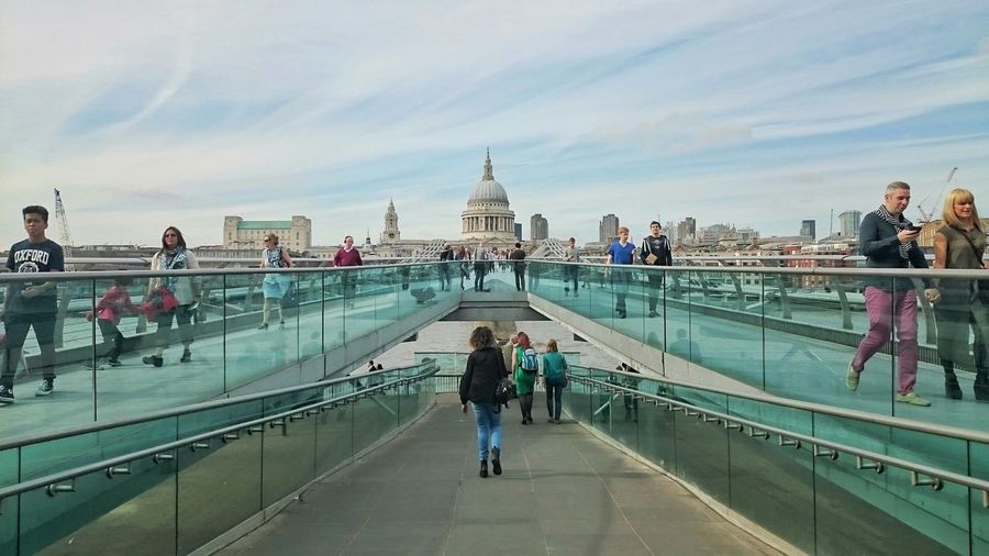 People walking on millennium bridge by st paul cathedral against sky