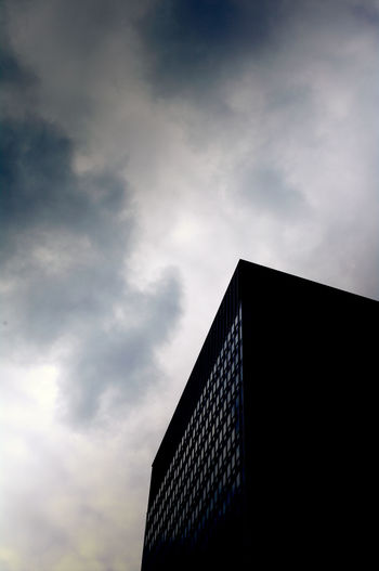 Low angle view of silhouette building against cloudy sky