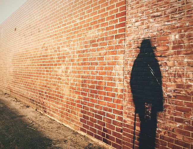 Shadow of man and woman walking on brick wall