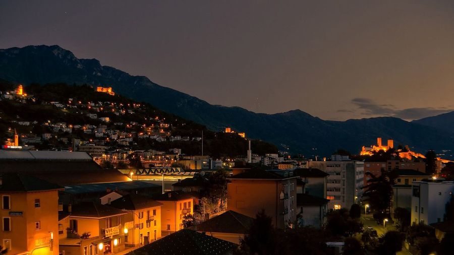 Illuminated town against mountains at dusk