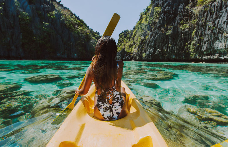 Rear view of woman kayaking in sea