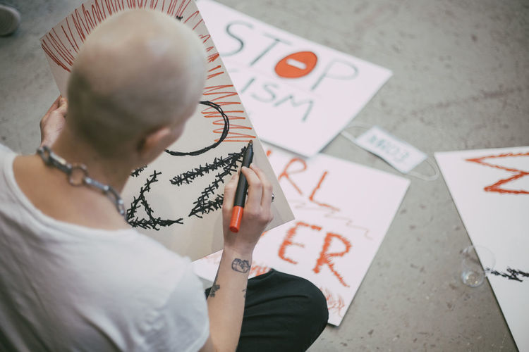 Rear view of bald female activist preparing signboard for social movement