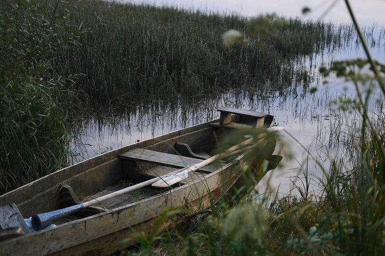 Abandoned boat on land by lake