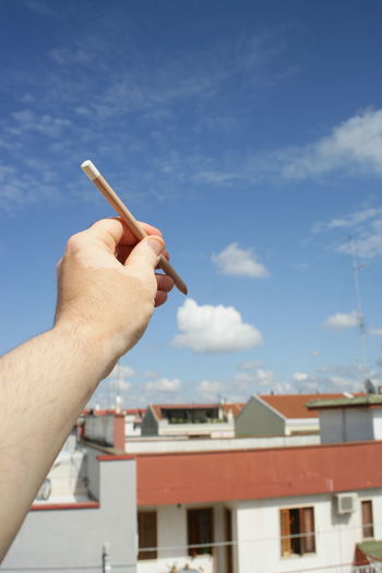 Midsection of person holding pencil against sky