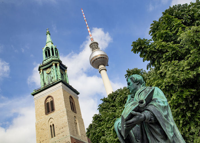 Low angle view of statue and fernsehturm against sky