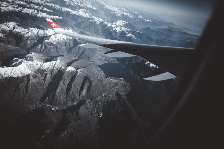 Airplane flying over mountains against sky